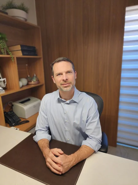 Foto do Dr. Phillipe Heckler, Médico Urologista, sentado no seu consultório.