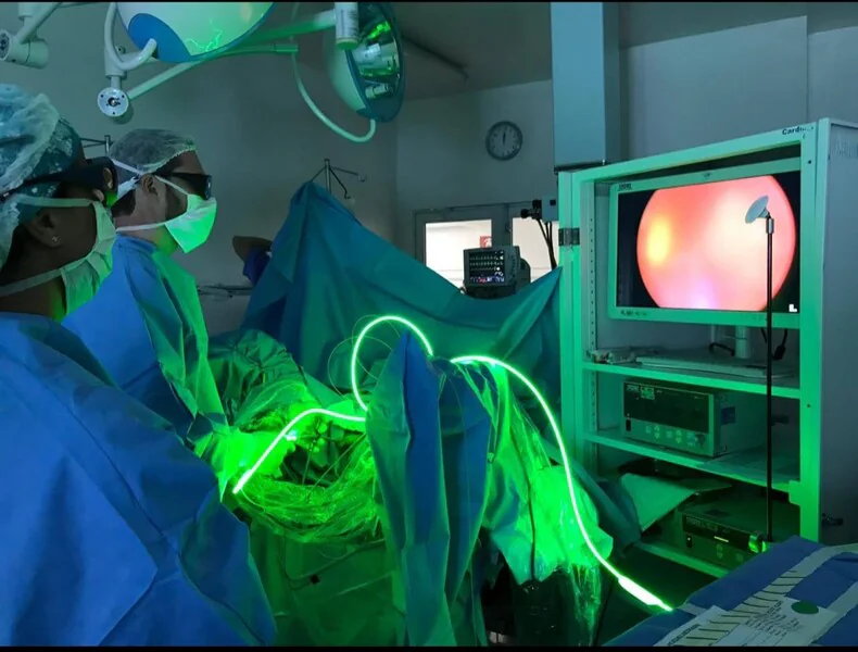 Dois profissionais de saúde realizando procedimento médico urologista com laser verde.