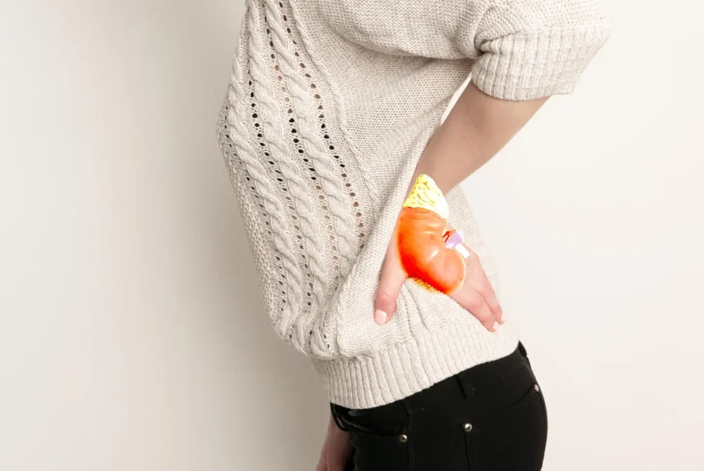 Imagem mostra um paciente deitado numa cama de hospital com as mãos voltadas para a região abdominal e uma expressão facial que sugere estar sentindo dor. A cena representa a importância do cuidado com quadrados de cálculo renal e do conhecimento sobre o que causa pedra nos rins.