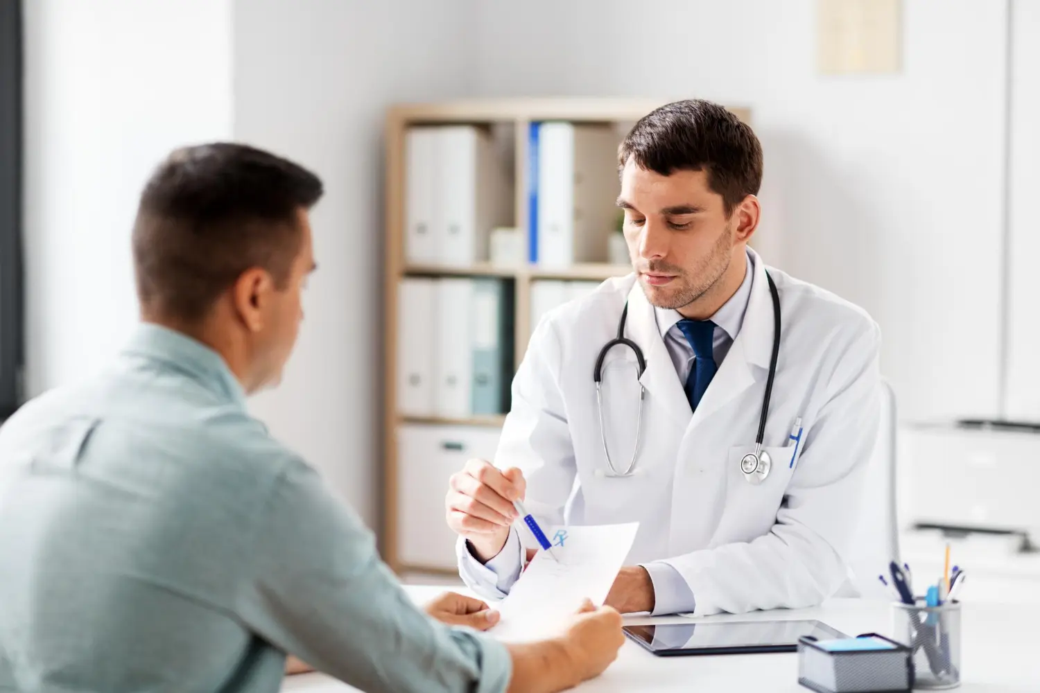 Médico urologista conversa com paciente, explicando se a cirurgia de vasectomia é reversível.