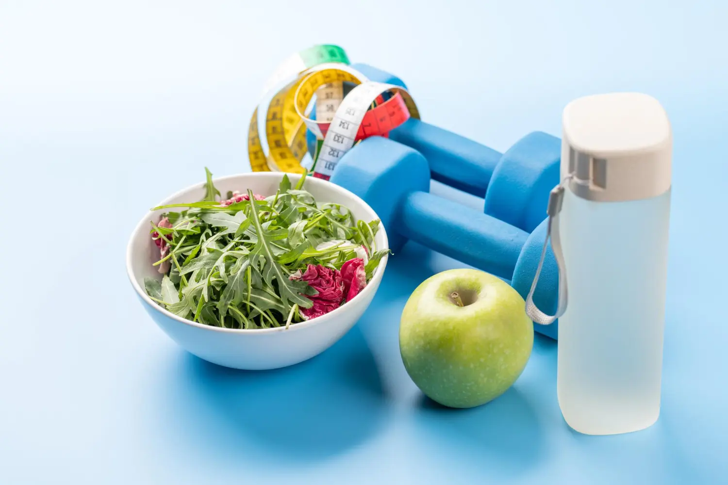 Imagem de alimentos saudáveis, água e halteres, simbolizando o estilo de vida ideal para evitar pedra nos rins.