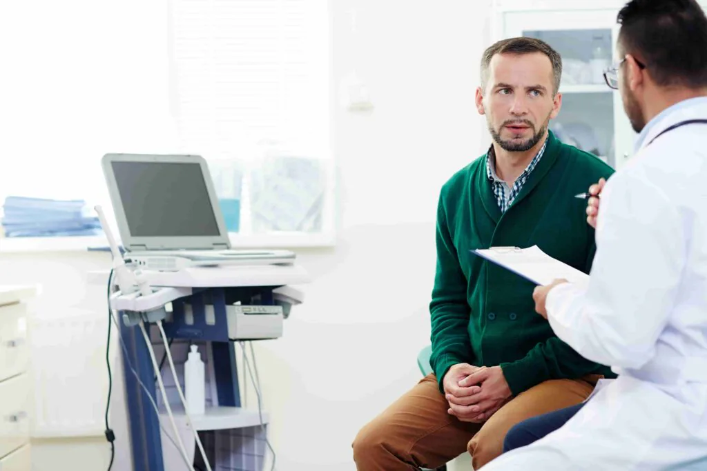Imagem de médico de jaleco branco examinando paciente sentado após entender quando consultar urologista.
